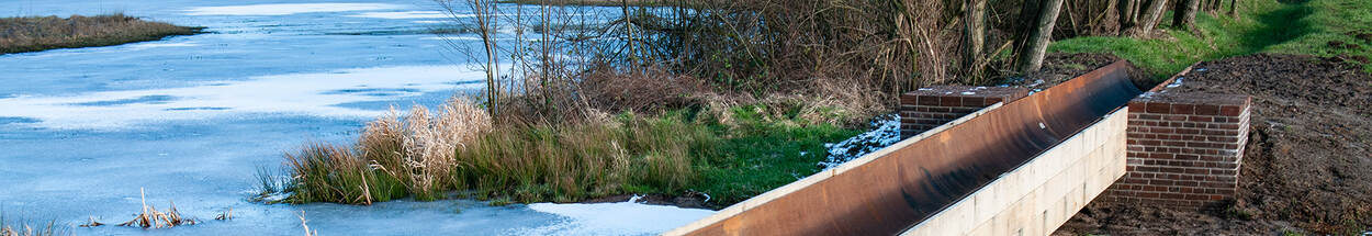 Een foto van een door mensen aangelegde geul naast bevroren water