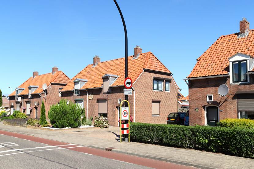 Aanzicht van meerdere twee-onder-één-kap-woningen en bijbehorende voortuinen