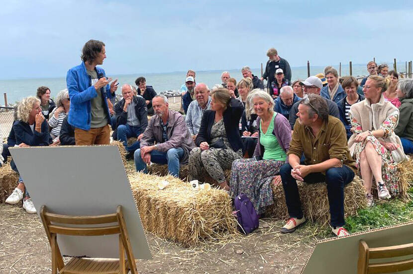 Mensen zitten op de dijk en luisteren naar een spreker