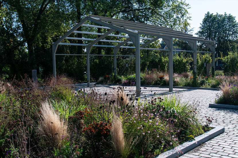 Een stalen frame met daaromheen plantvakken waar verschillende planten in staan.